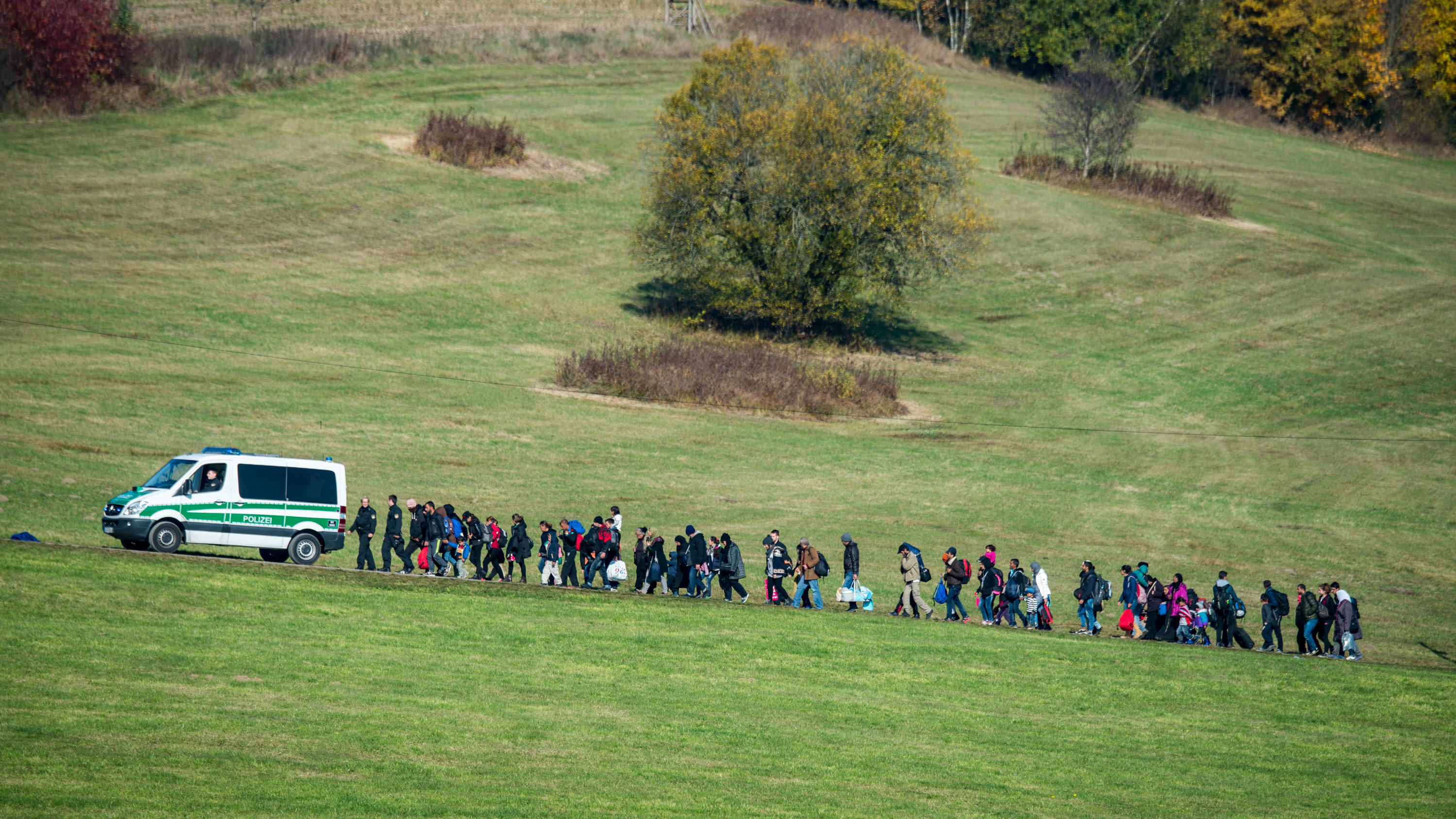 Merkel gegen Seehofer, CDU gegen CSU - sprengt der Asyl-Streit die Regierung? ARCHIV - 27.10.2015, Bayern, Wegscheid: Flüchtlinge gehen nahe Wegscheid hinter einem Fahrzeug der Bundespolizei. (zu dpa «Streit mit Merkel: Seehofer verschiebt Vorstellung seines Asylplans » vom 11.06.2018) Foto: Armin Weigel/dpa +++ dpa-Bildfunk