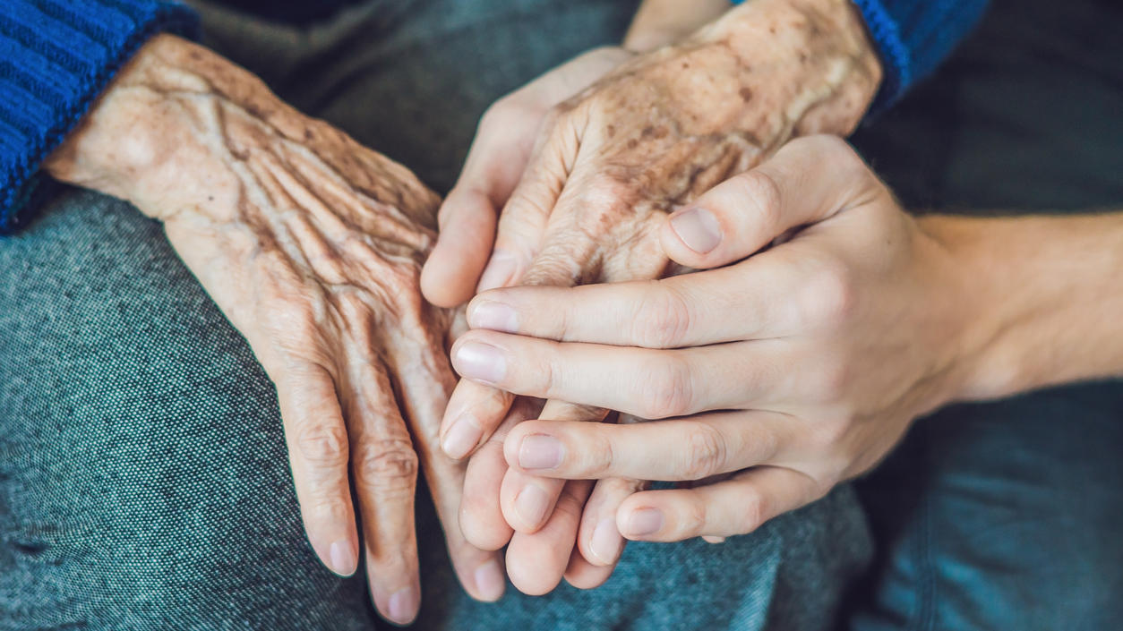 Barmer-Pflegereport 2018: Pflegende Angehörige oft überlastet Eine jüngere Hand liegt auf der Hand einer älteren Person.