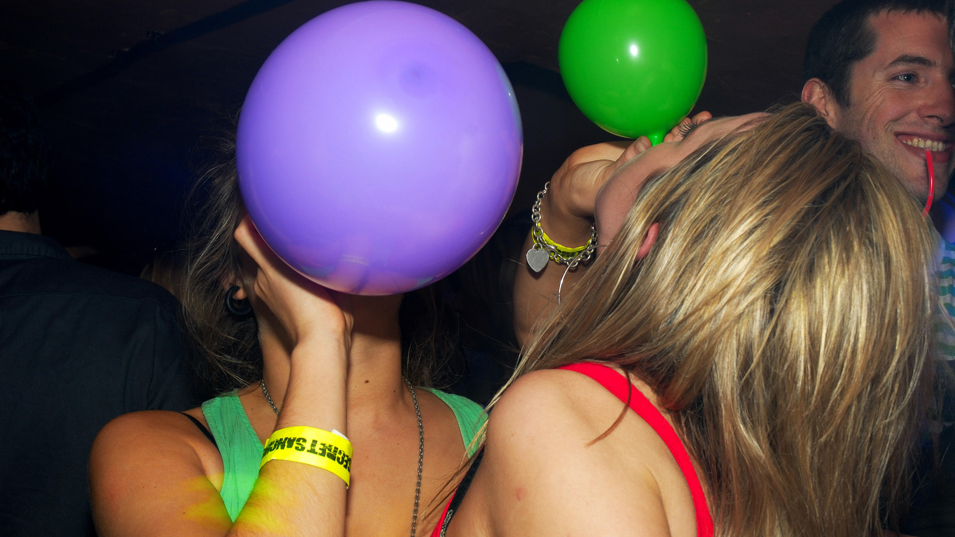 Lachgas: Die unterschätzte Party-Droge aus Sahnekapseln Zwei Frauen ihnalieren Lachgas aus bunten Luftballons.