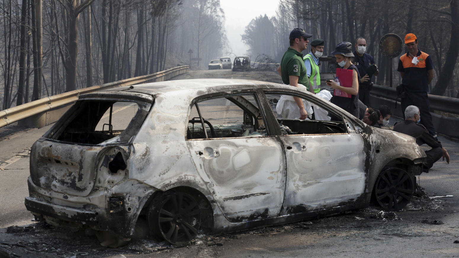 Mehr als 60 Tote nach Waldbrand in Portugal: Flammen fressen sich weiter vorwärts Polizisten stehen am 18.06.2017 auf der Landstraße zwischen Castanheira de Pera und Figueiro dos Vinhos (Portugal) neben ausgebrannten Autos. Der verheerende Waldbrand mit mehreren Toten in Portugal ist der Polizei zufolge durch Blitzschlag ausgelöst